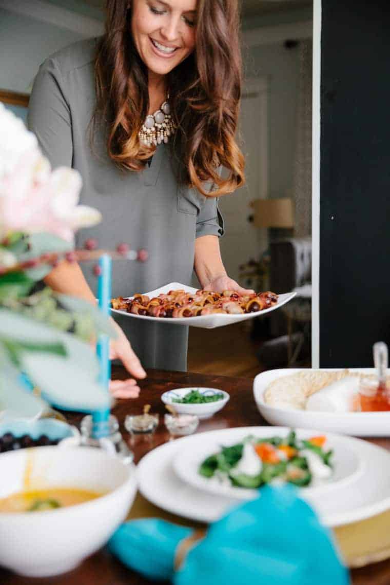 woman placing a plate of appetizers onto a set table