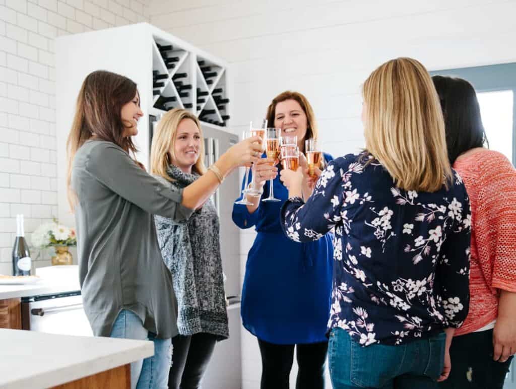 How to Host a Last-Minute Holiday Open House Party with a group of women in a kitchen raising champagne in a cheers