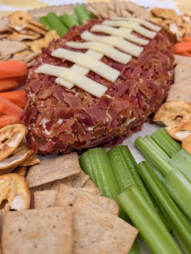 close up of Cheddar Bacon Ranch Football Cheese Ball surrounded by crackers and veggies