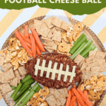 Football-shaped cheese ball with bacon and provolone laces, served on a platter with crackers, celery, and carrots.