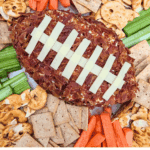 Overhead view of a cheddar bacon ranch football cheese ball with dippers.