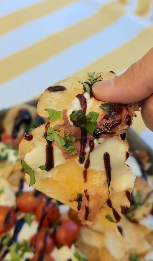 a platter of The Viral Potato Chip Charcuterie: Caprese Style someone grabbing a chip off of the tray.