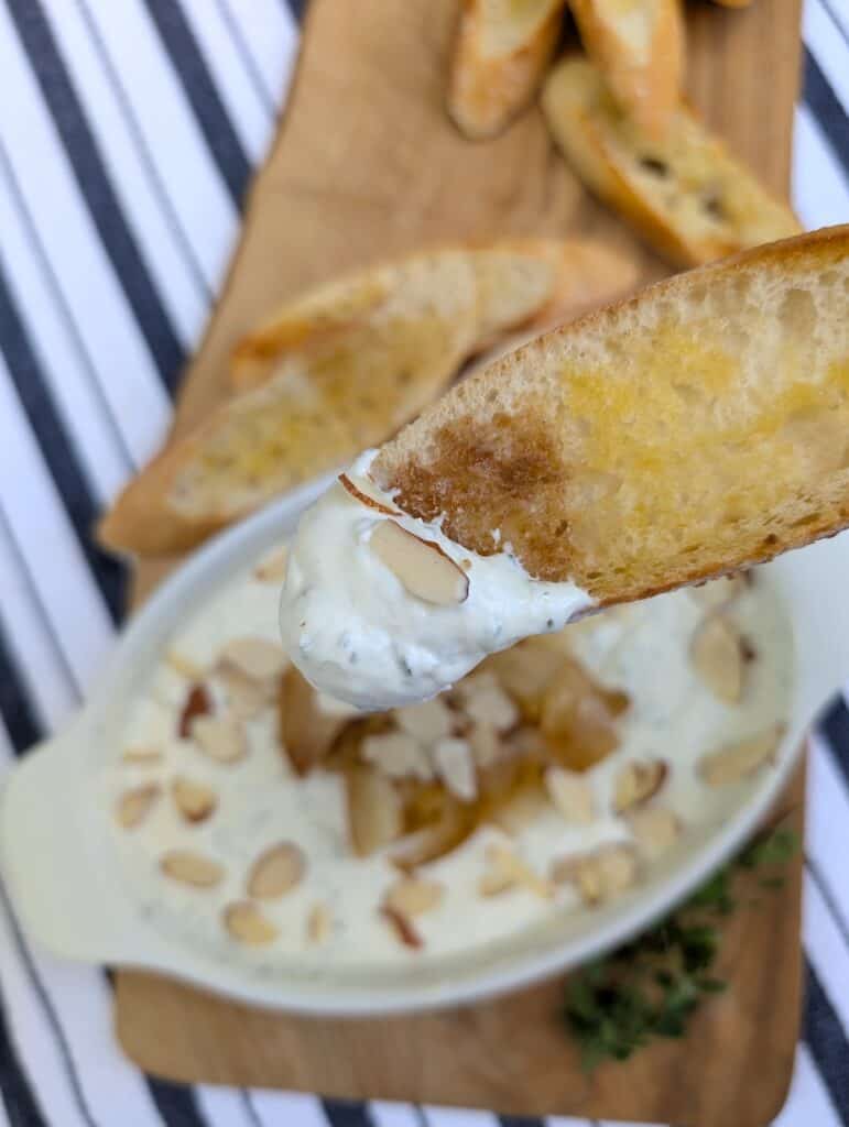 a picture of a piece of crostini dipped in the Creamy Whipped Goat Cheese Dip 