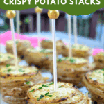 A close-up, slightly blurred background shot of several baked Garlic & Parmesan Crispy Potato Stacks, held together with appetizer picks. The foreground stack is clear, showing crispy edges. Text overlay reads: "easy & delicious Garlic & Parmesan Crispy Potato Stacks."