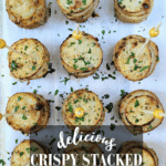 A top-down view of nine individual, golden-brown Crispy Stacked Potatoes on a white serving board, each secured with a gold-tipped appetizer pick and sprinkled with herbs. Text overlay reads: "delicious Crispy Stacked Potatoes in muffin tins."