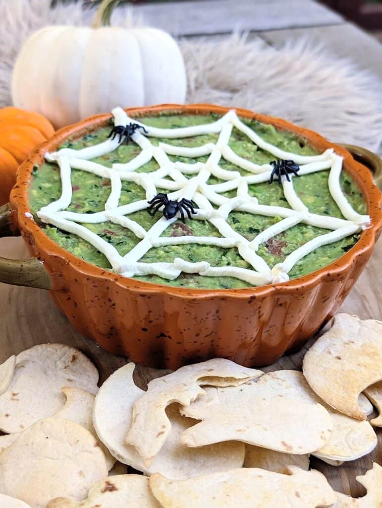 shot of assembled Halloween Guacamole with Spooky Chips on a wooden board