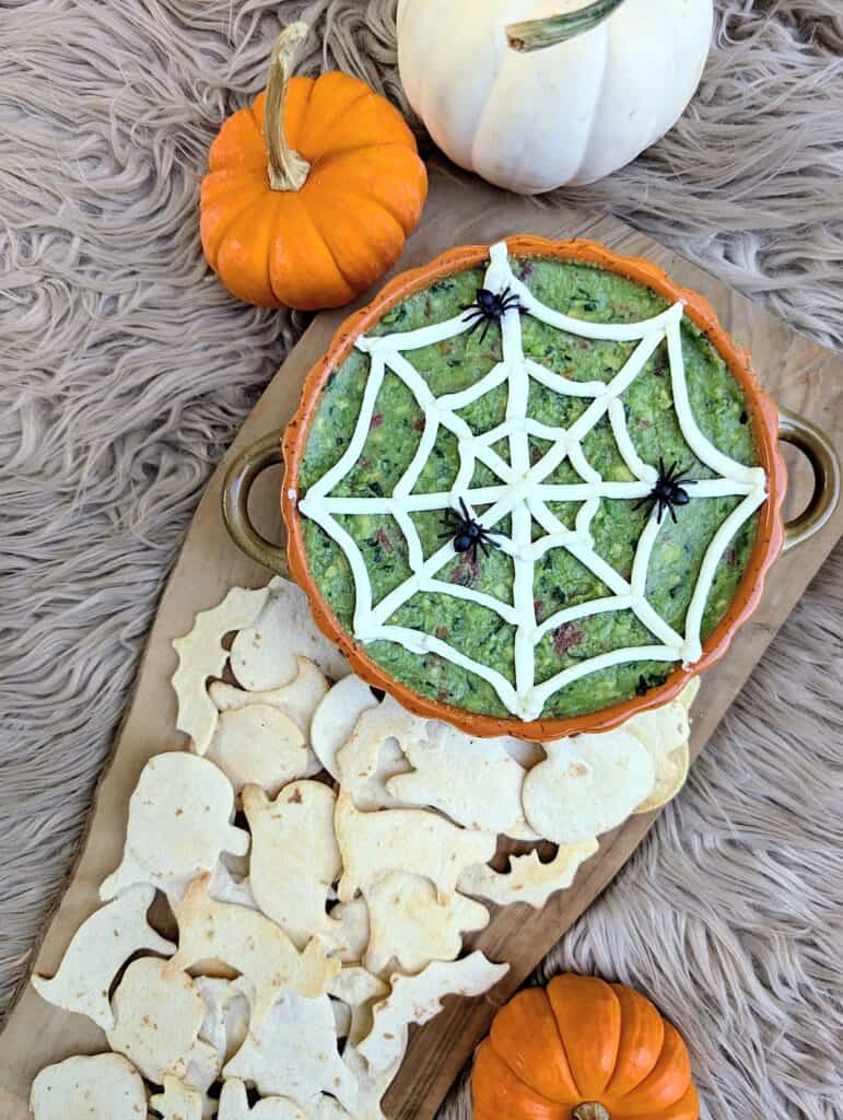 overhead finished shot of The Ultimate Halloween Guacamole with Spooky Chips surrounded by mini pumpkins