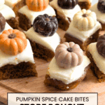 A collection of small, square pumpkin spice cake bites with white frosting, decorated with various fall-themed chocolate candies on a wooden cutting board. Text overlay reads: "Pumpkin Spice Cake Bites, Store Bought Cake Makeover."
