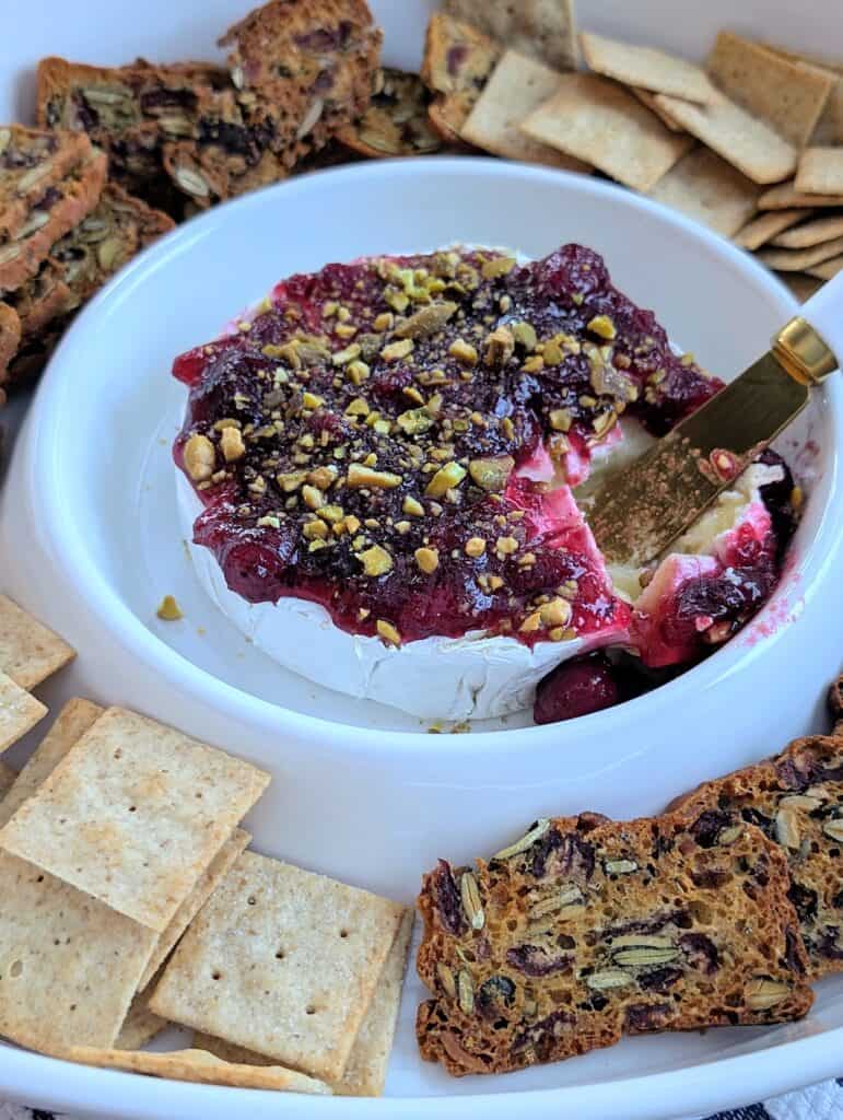 Easy Baked Brie with Cranberry Sauce and Pistachios with spreader serving