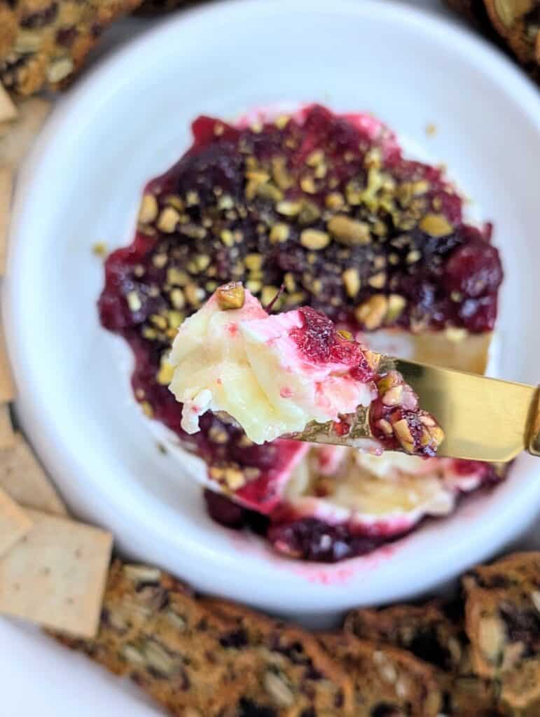 Baked Brie with Cranberry Sauce and Pistachios on a spreader knife