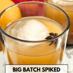 A close-up shot of a glass tumbler containing a spiked apple cider cocktail over a large ice sphere and garnished with star anise. Text overlay reads: "Big Batch Spiked Apple Cider Cocktail with Fireball Whisky."