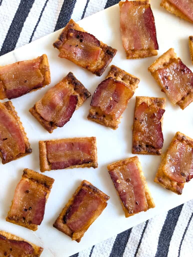 Candied Bacon Crackers on white platter with striped cloth underneath.