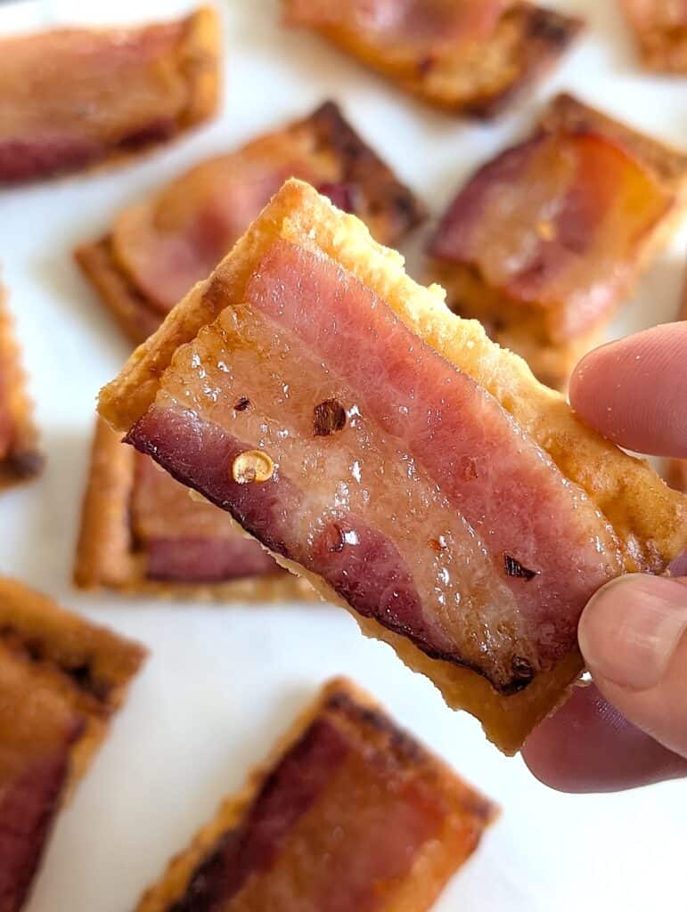 close up shot of hand holding up a candied bacon cracker