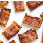 Close-up of multiple finished candied bacon Club cracker appetizers on a white surface. The text overlay reads: "3-ingredient CANDIED BACON CLUB CRACKERS APP."