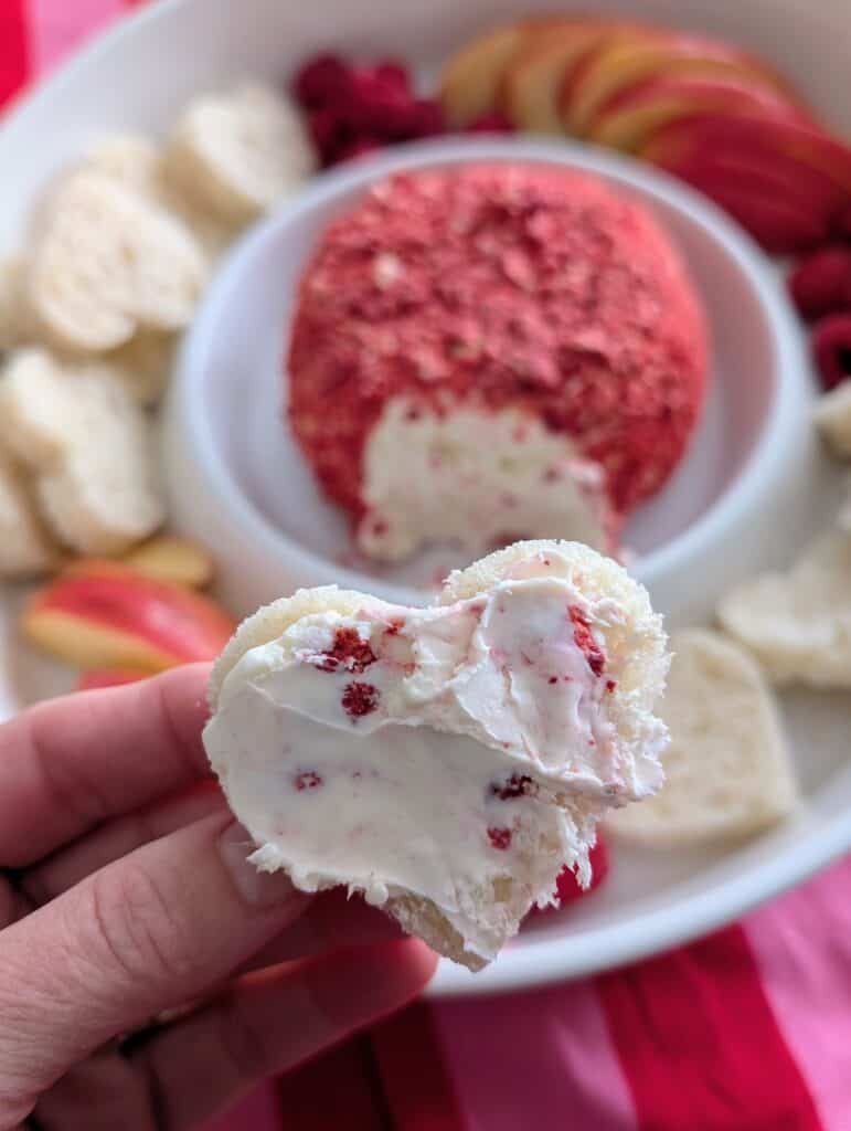 a smear spread on a heart shaped bread piece held up by a hand
