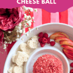 Strawberry cream cheese dessert cheese ball on a white platter with apple slices, raspberries, and heart-shaped bread.