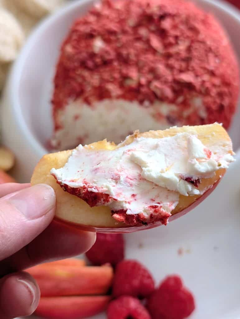 a smear on an apple slice held up by a hand