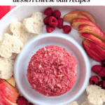 Strawberry cheese ball in center of platter with raspberries, apple slices, and heart-shaped bread.