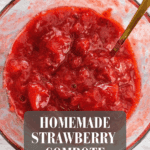 Close-up of thick homemade strawberry compote in glass bowl with spoon.