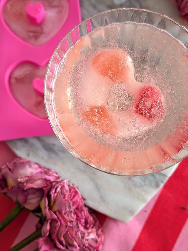 overhead close up of ice cube in a glass with pink flowers and ice cube mold