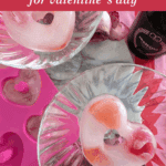 Heart-shaped ice cube mold filled with water and candy before freezing and finished heart ice cubes served in a sparkling drink.