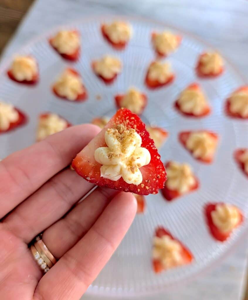 hand holding up one cheesecake deviled strawberry