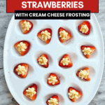 Deviled strawberries arranged on an oval white platter with cream cheese frosting and graham cracker crumbs.