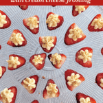 Strawberry halves filled with cream cheese frosting arranged in a circular pattern on a glass platter.