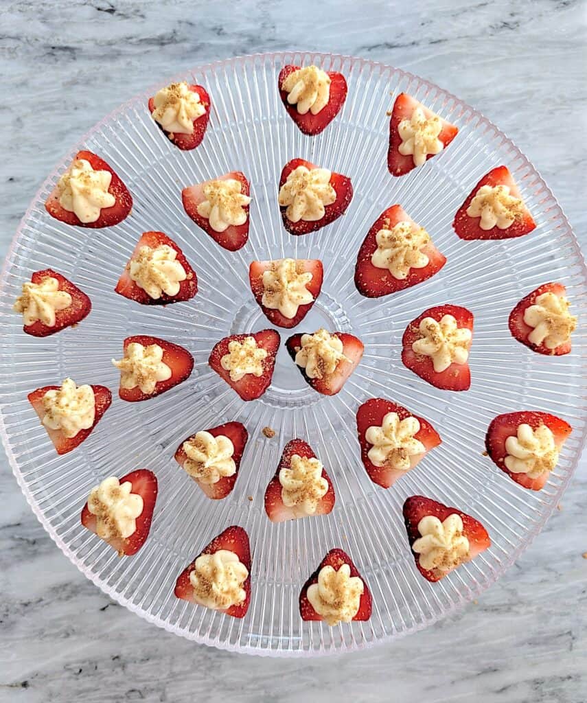 overhead shot of The Easiest Cheesecake Deviled Strawberries Recipe on a glass cake stand
